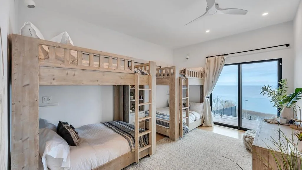 Un dormitorio con literas de madera, una ventana grande y vistas al agua.