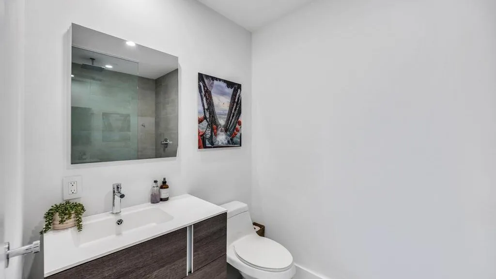 Un baño luminoso con lavabo, espejo e inodoro.