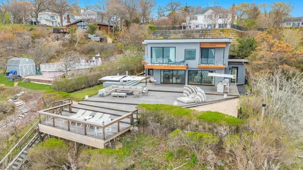 Una casa moderna da a una amplia terraza exterior con asientos y jardines.