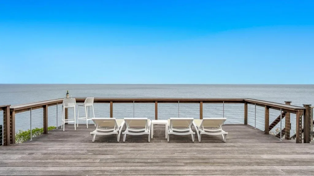 Una terraza frente al agua con asientos reclinables da al mar tranquilo.