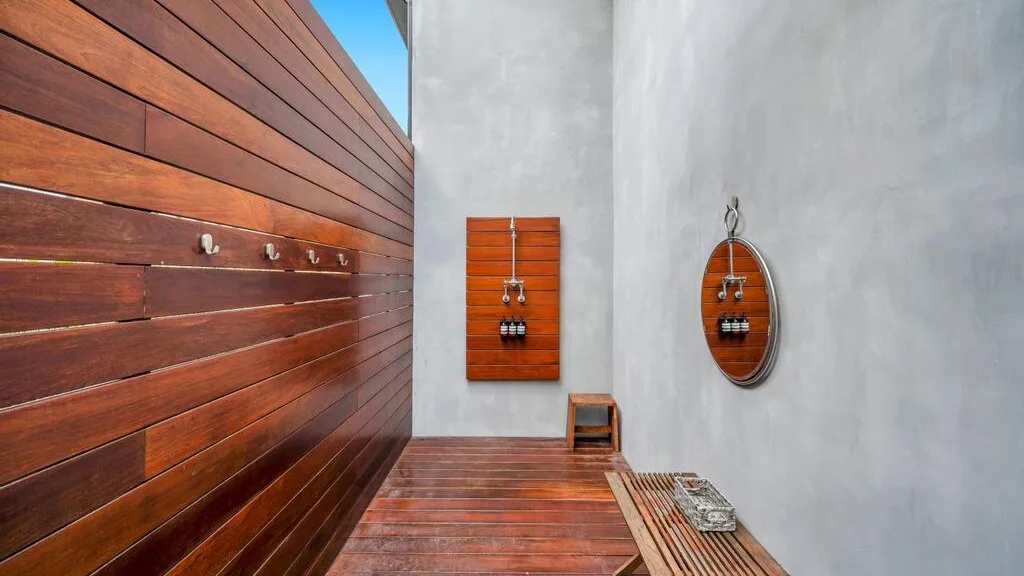 Una zona de ducha con paredes de madera y accesorios metálicos.