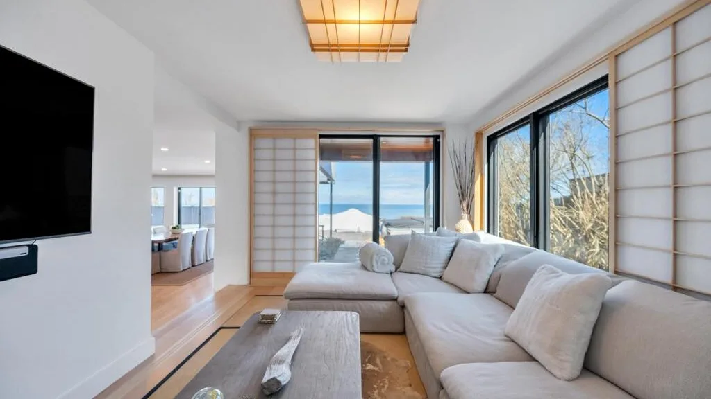 Una sala luminosa con asientos seccionales y grandes ventanales con vista al agua.