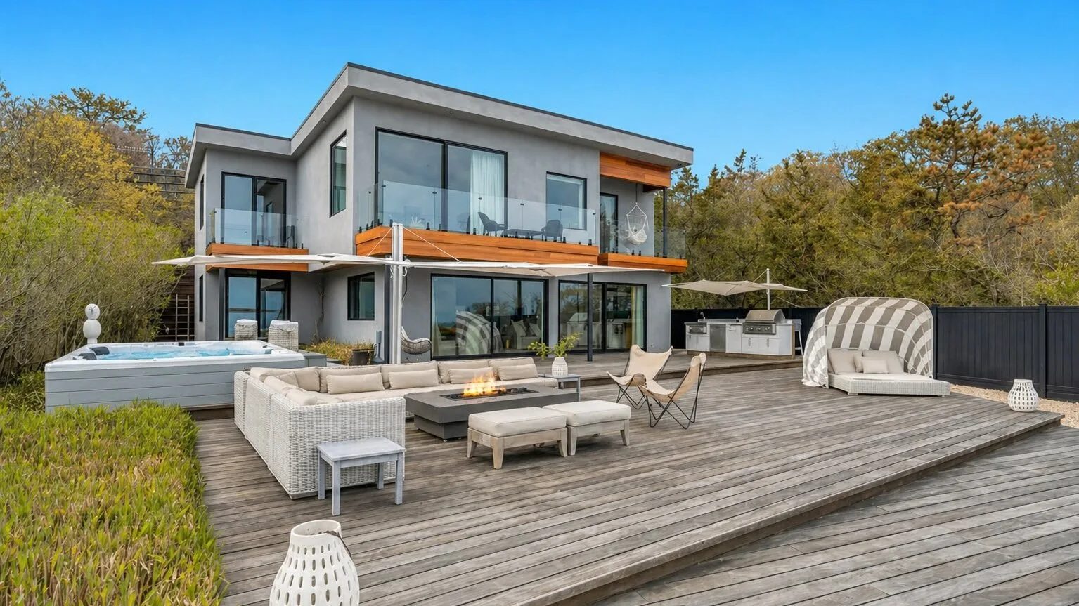 Casa moderna con una amplia terraza de madera y asientos al aire libre.