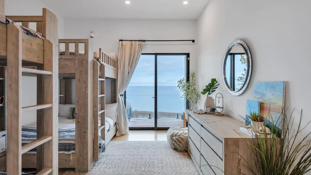 Un dormitorio luminoso con literas y puertas corredizas de vidrio con vista al mar.