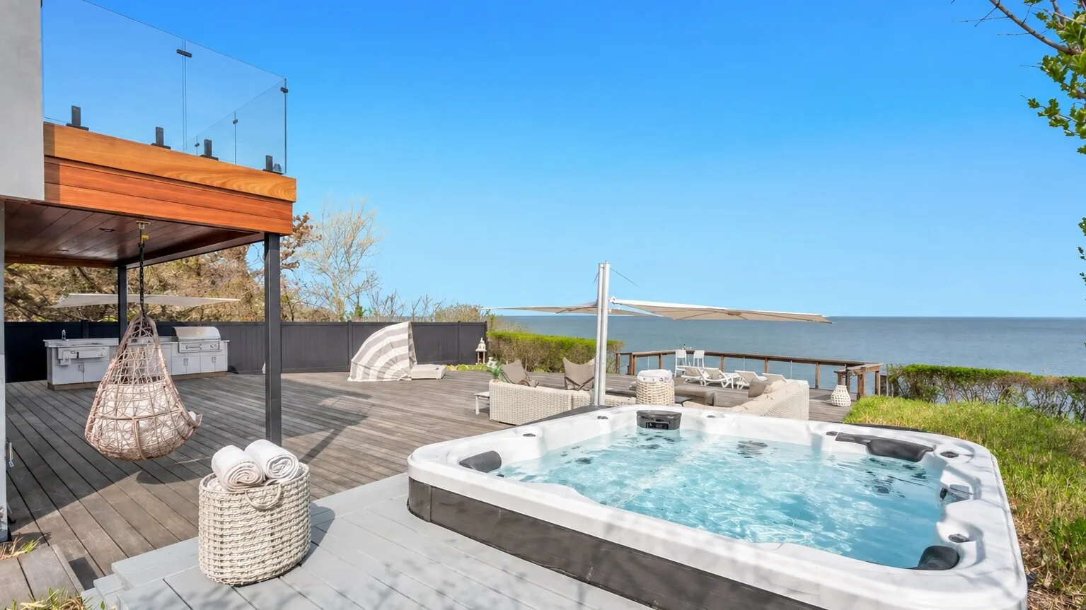 Una terraza al aire libre cuenta con una bañera de hidromasaje junto al mar.