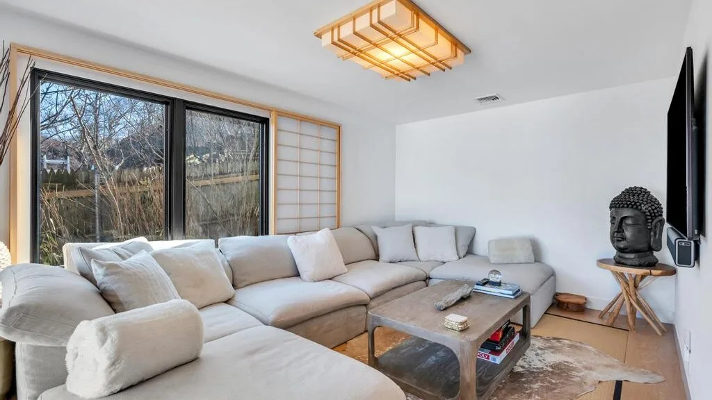 Una sala luminosa con asientos seccionales, una mesa de centro y ventanas amplias.