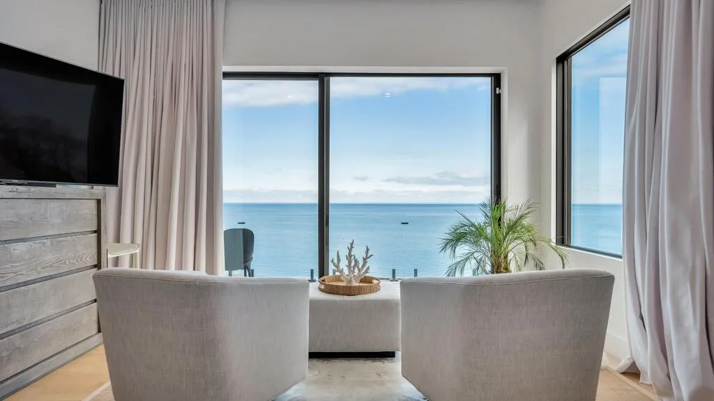 Una sala luminosa con asientos frente a grandes ventanas con vista al mar.
