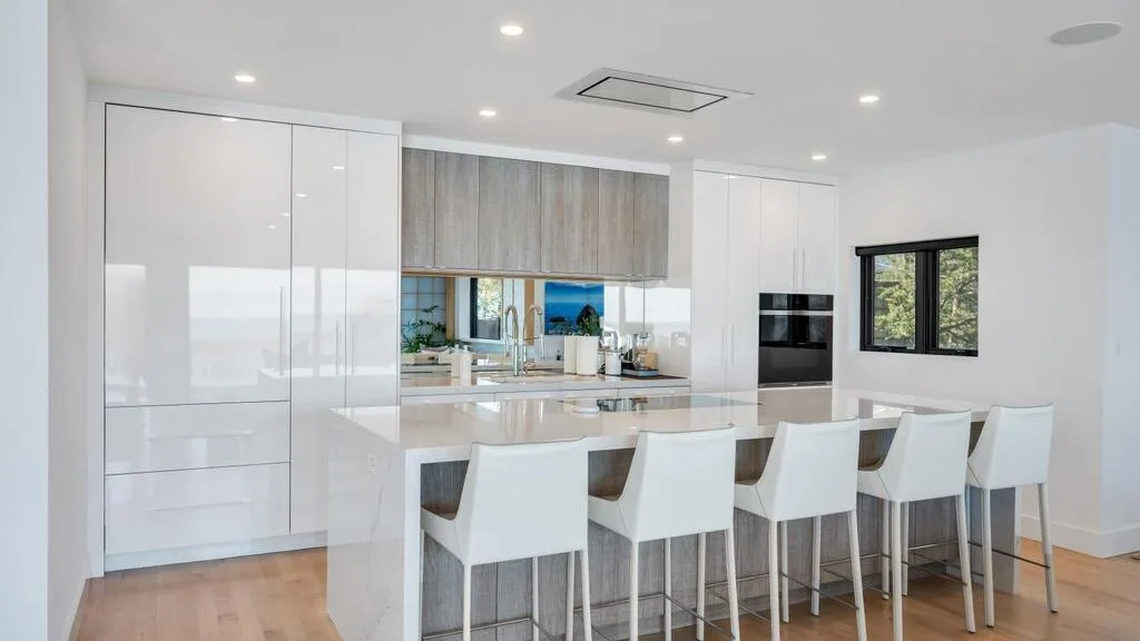 Una cocina luminosa con una isla larga y asientos blancos.