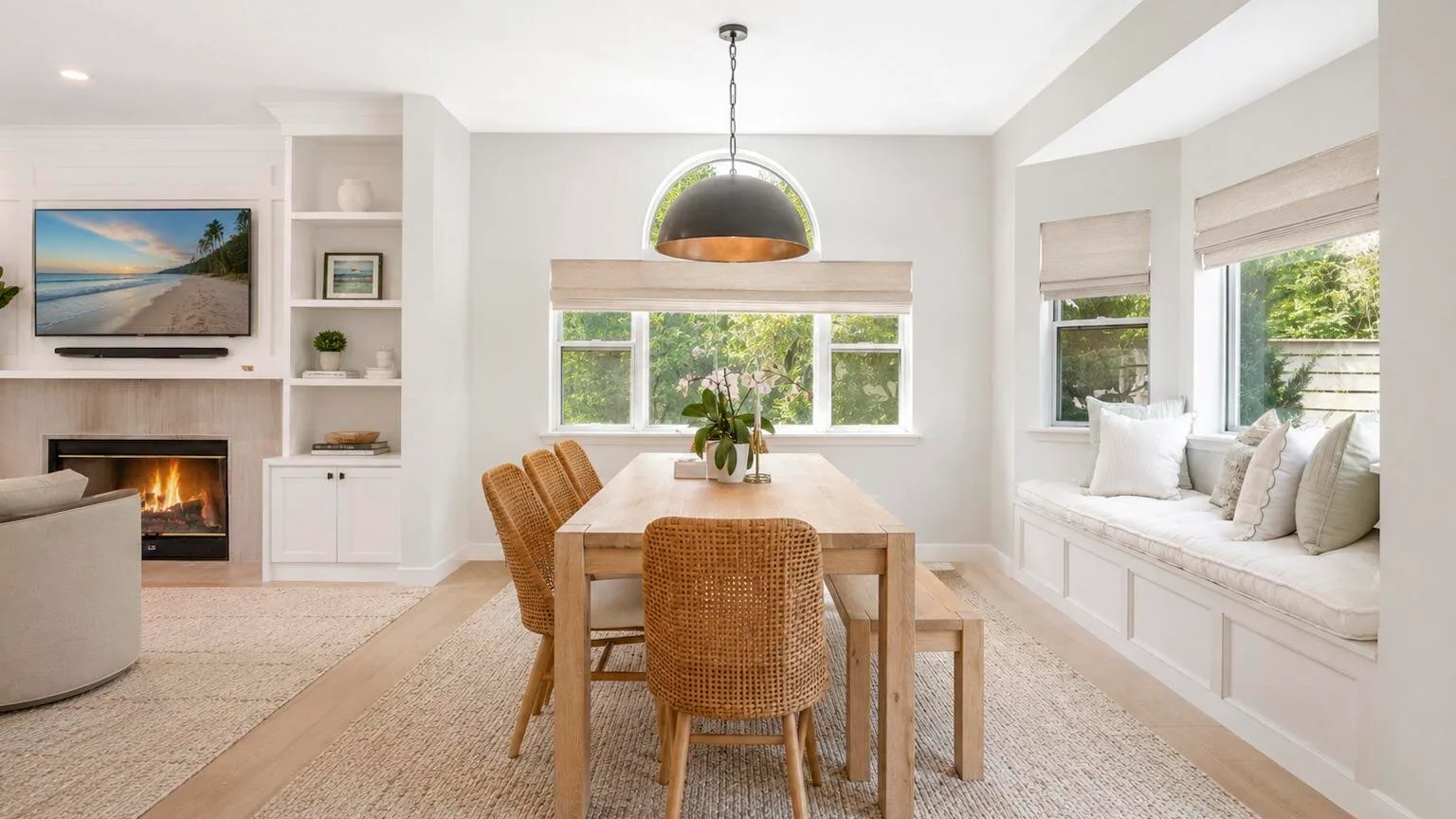 Un comedor luminoso con una mesa de madera, asientos tejidos y un banco junto a la ventana.