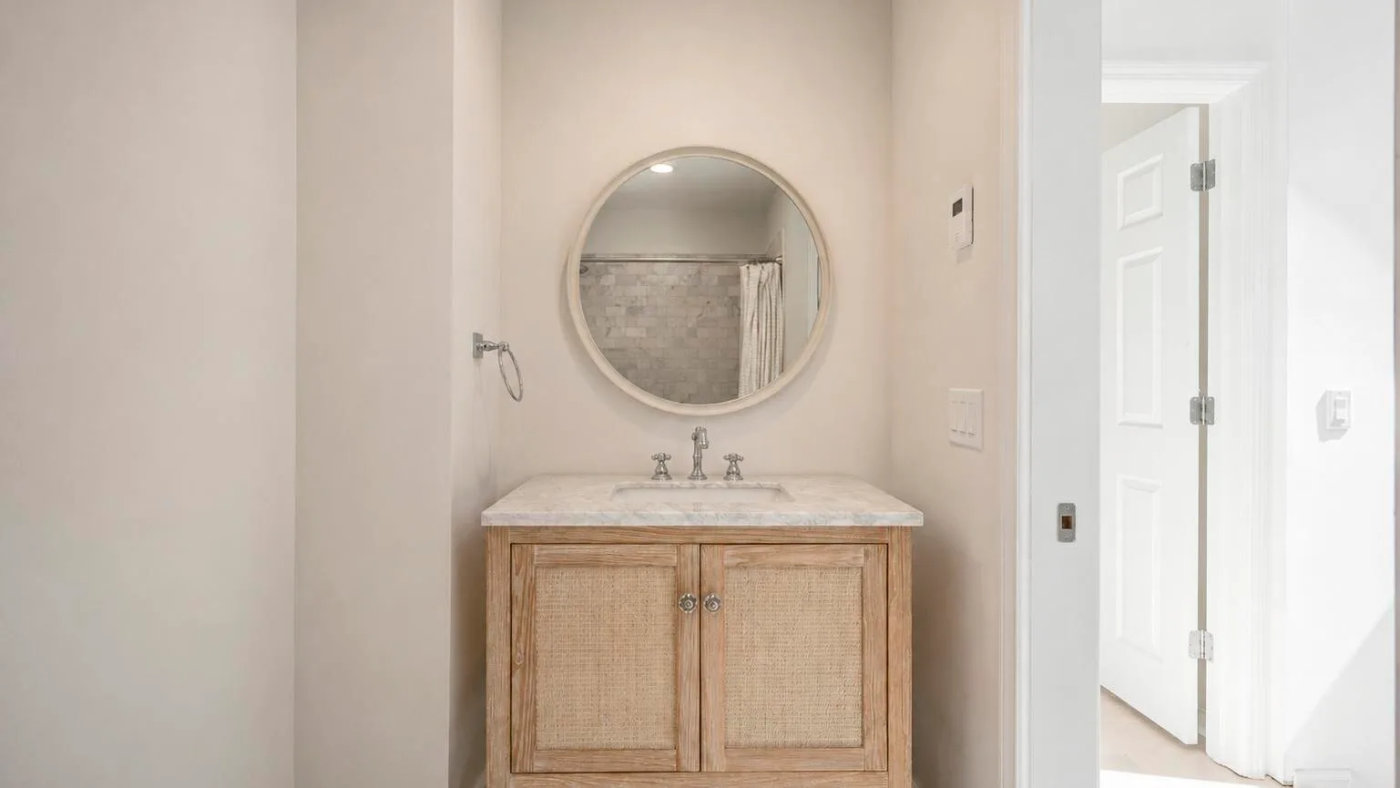 Un lavabo de baño con un espejo redondo encima.