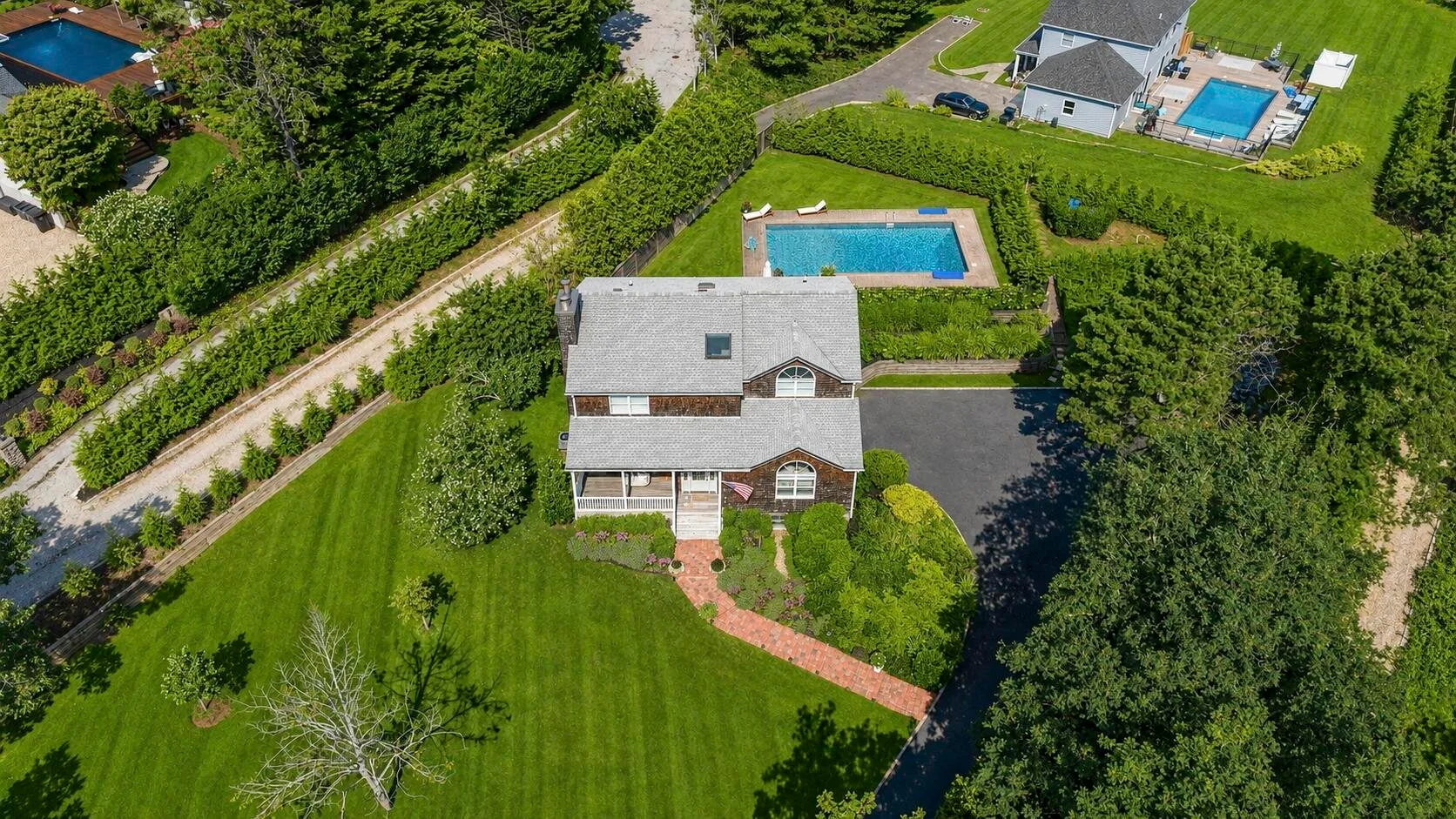 Vista aérea de una casa y sus jardines, con una piscina cercana.