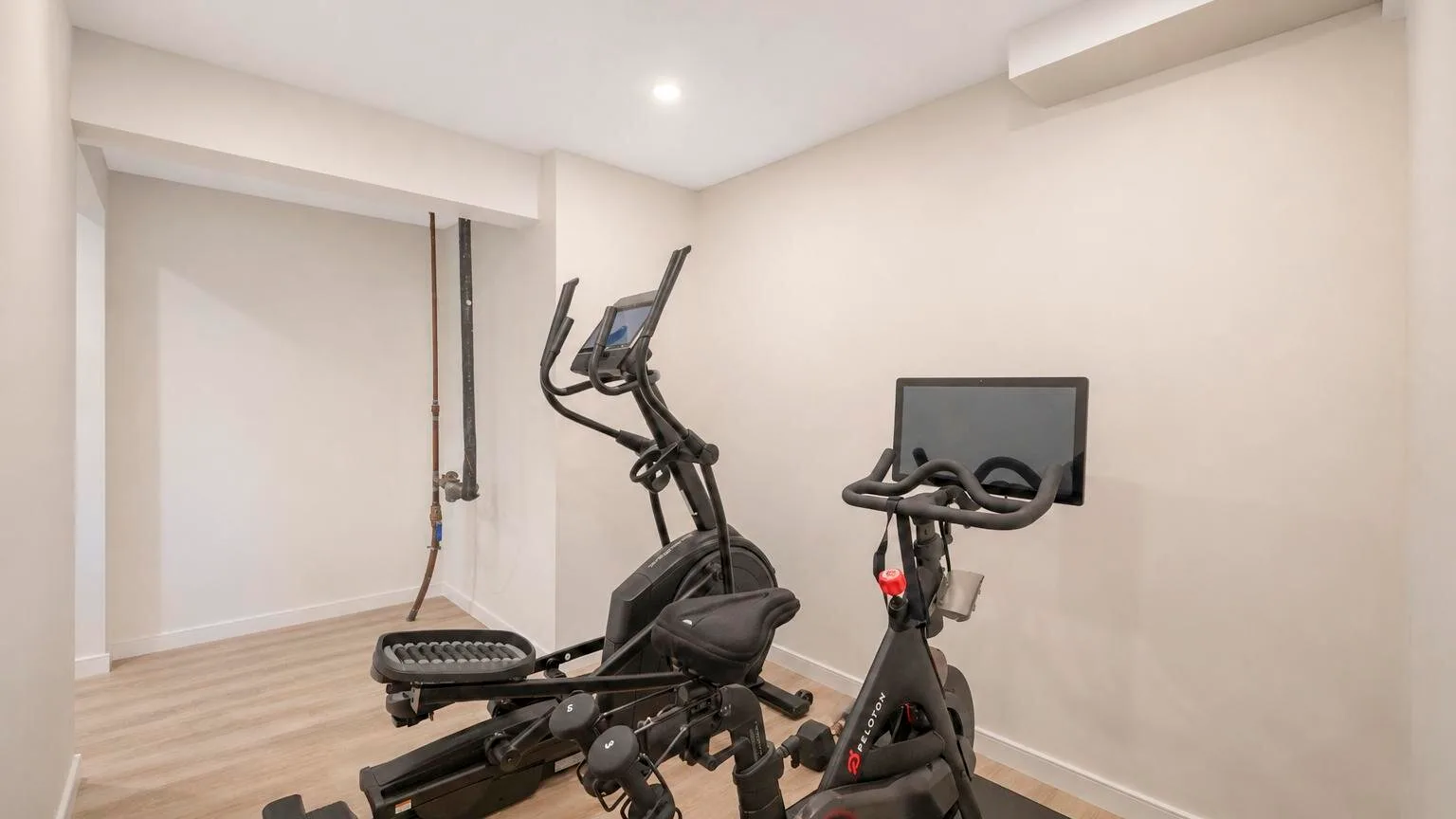 Una zona de ejercicio en casa con equipos de entrenamiento y una pantalla en la pared.