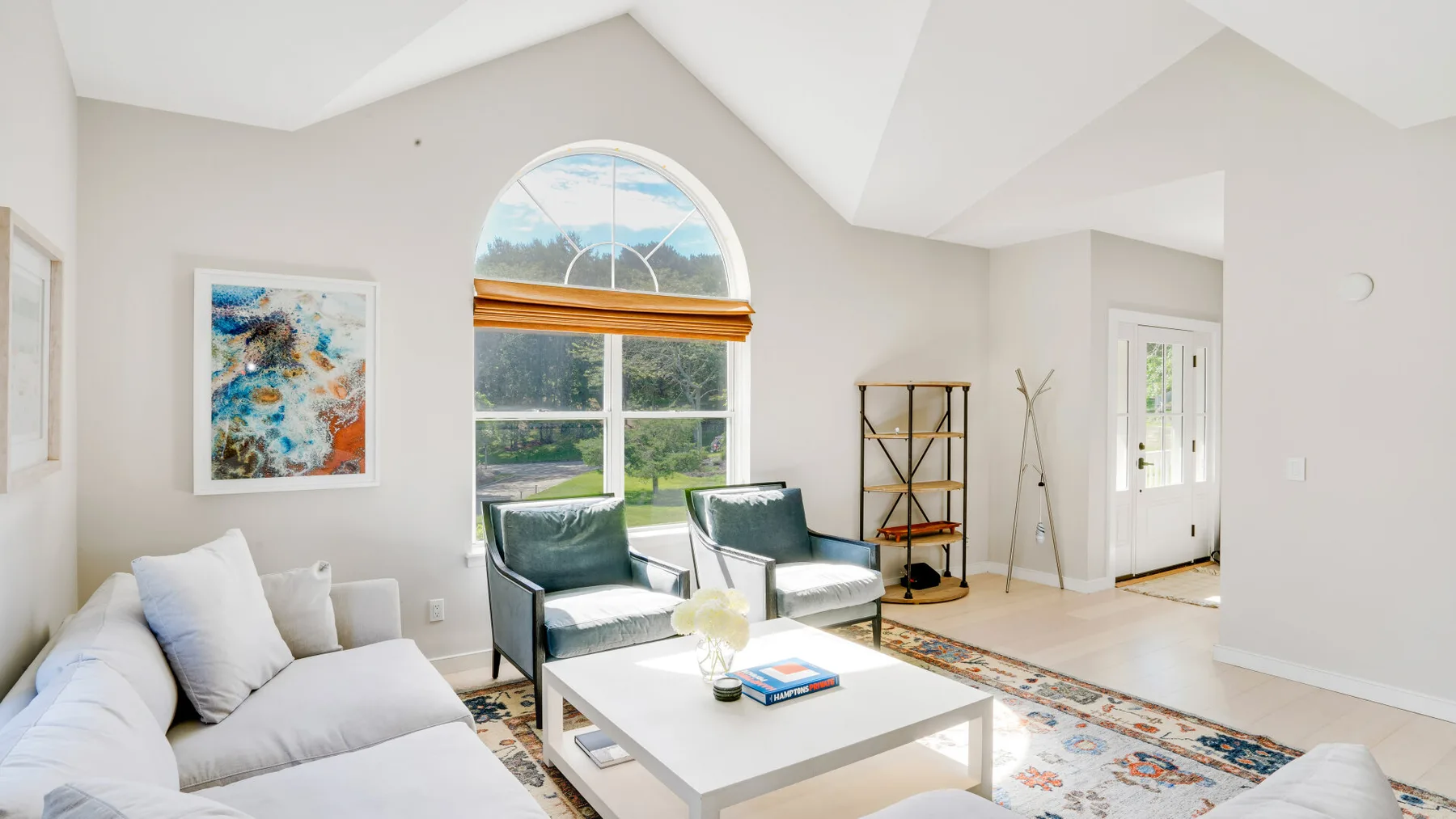 Una sala luminosa con asientos, una mesa de centro y una gran ventana arqueada.
