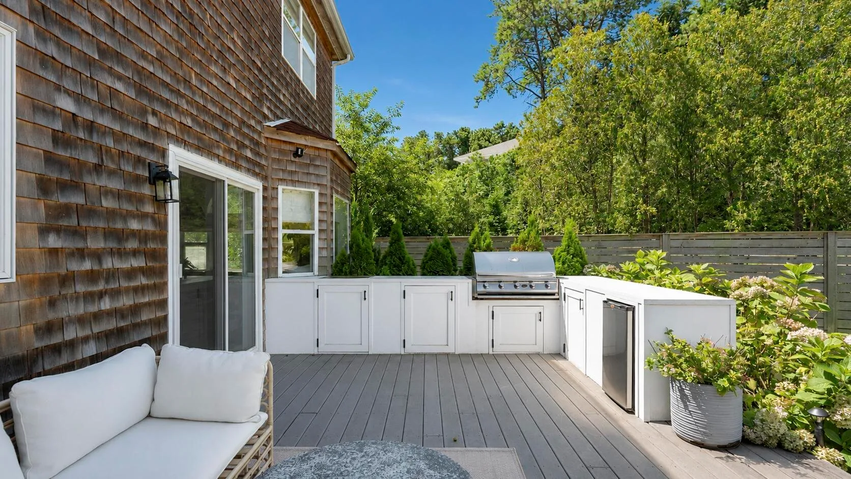 Una terraza exterior con una encimera y parrilla junto a una casa.