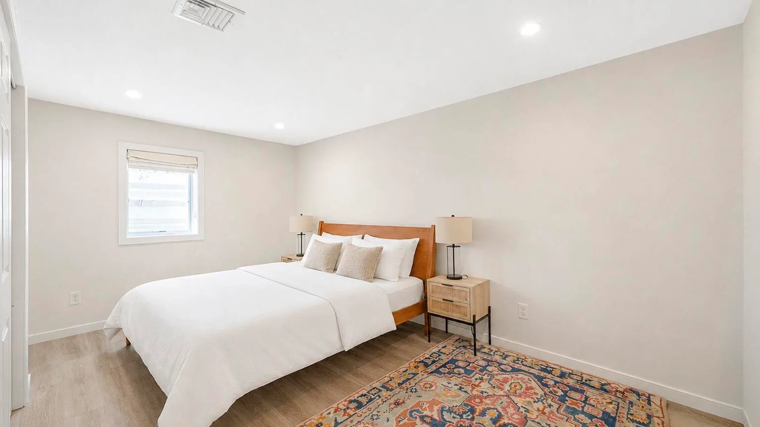 Un dormitorio con una cama tendida y una alfombra colorida.