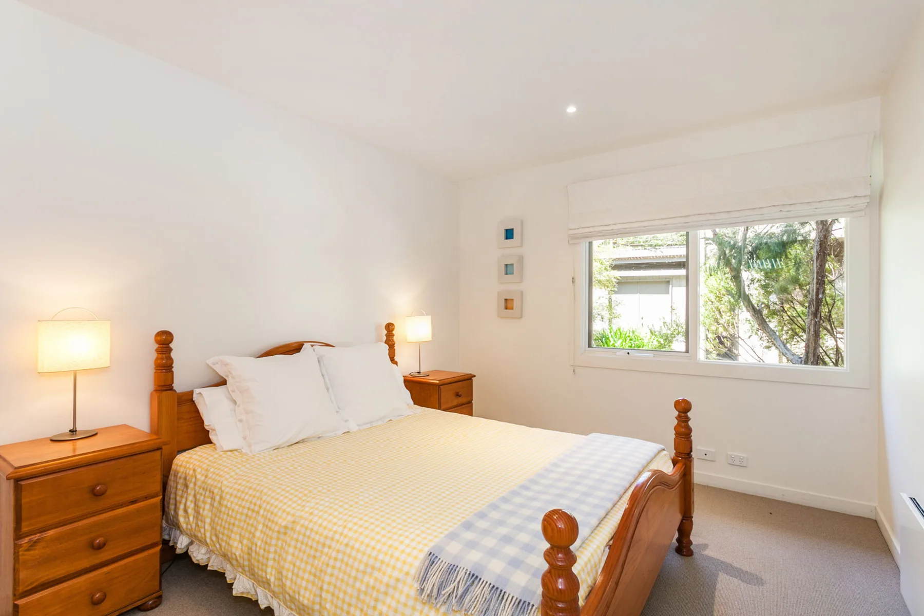 A bright bedroom with a wooden bed and a wide window.