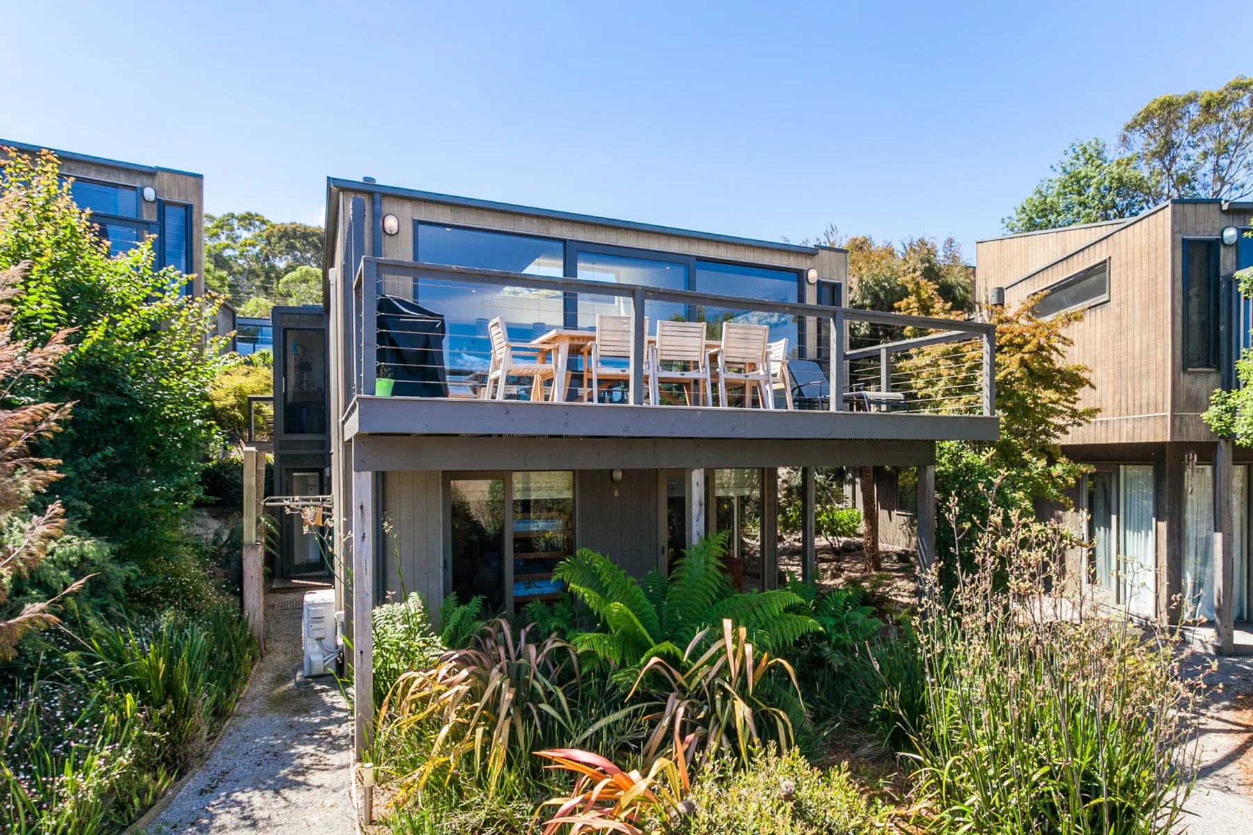 Modern buildings surround an outdoor patio with seating and glass doors.