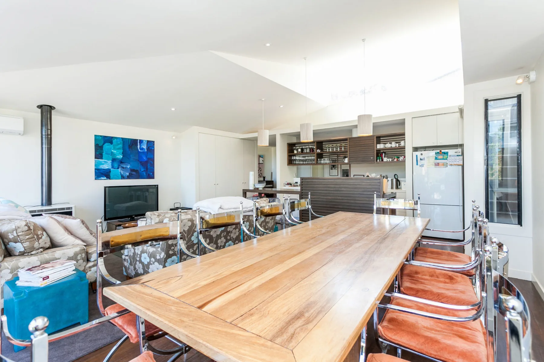 A dining area with a long wooden table and orange seating.