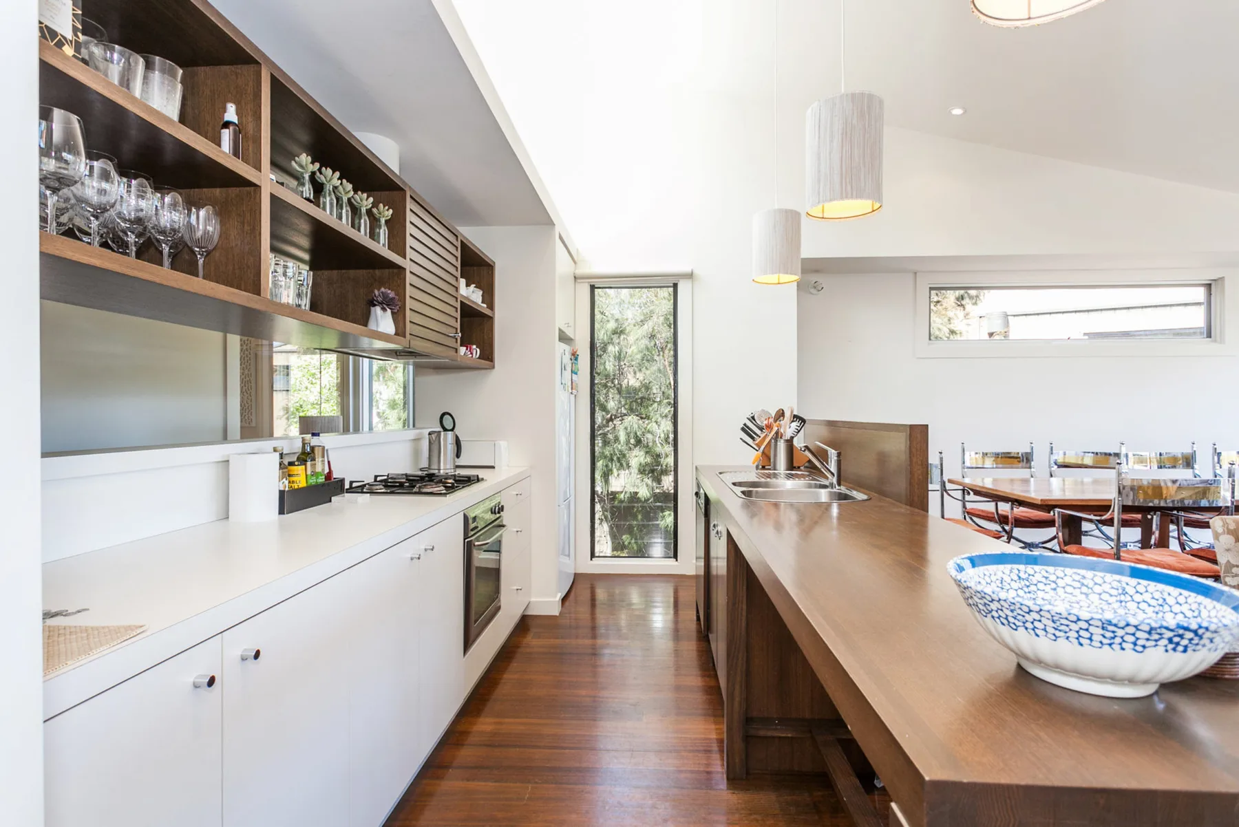 A bright kitchen with a long counter and open shelving.