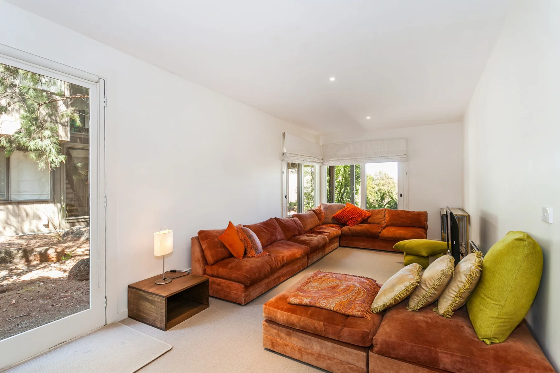 A bright living room with sectional seating and large windows.