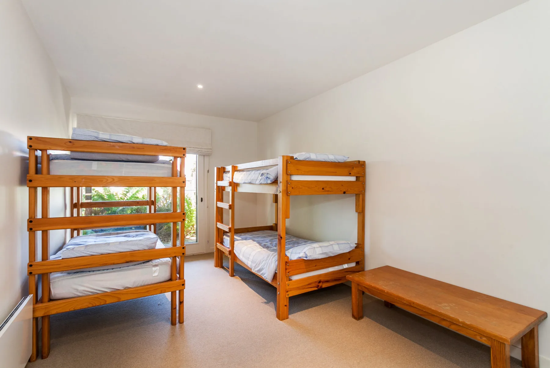 A bright bedroom with wooden bunk beds and a low table.