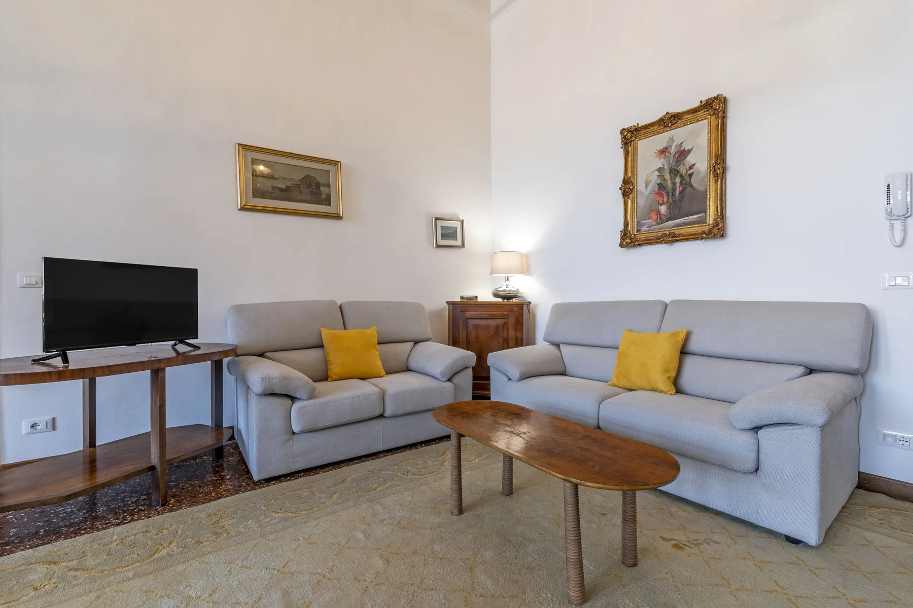 A living room with light-colored seating, a television, and a wooden coffee table.