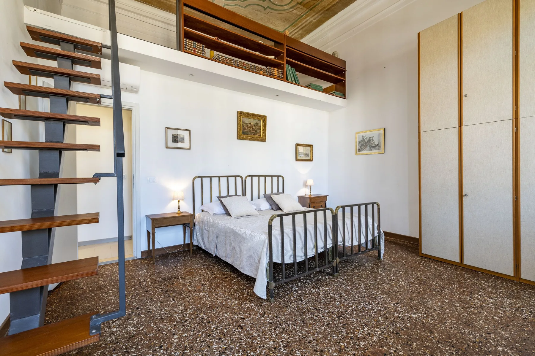 A bedroom with a metal bed, a ladder, and a raised sleeping area.
