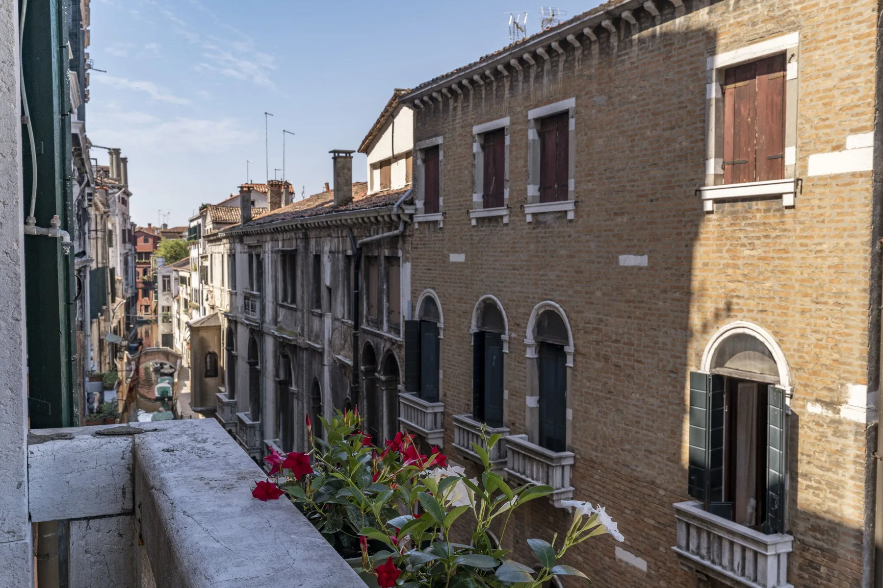 A narrow canal-side street lined with historic brick buildings and flower boxes.