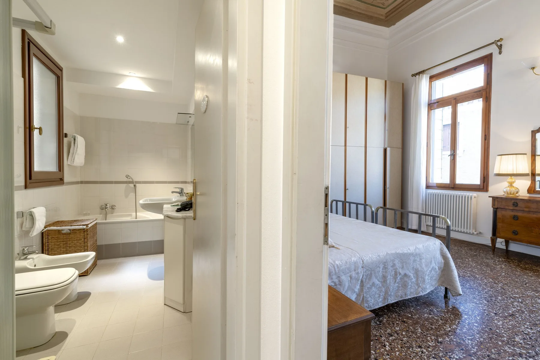 A bedroom with a bed is visible beside a bathroom with a bathtub and toilet.
