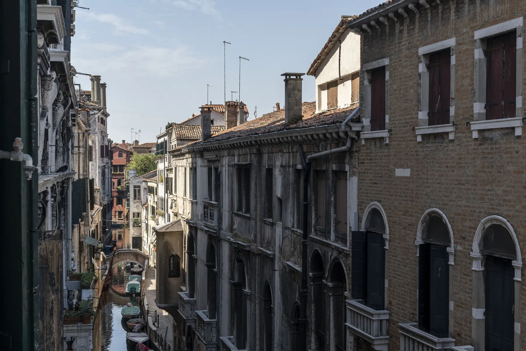 A narrow city canal-side street runs between closely spaced historic buildings.