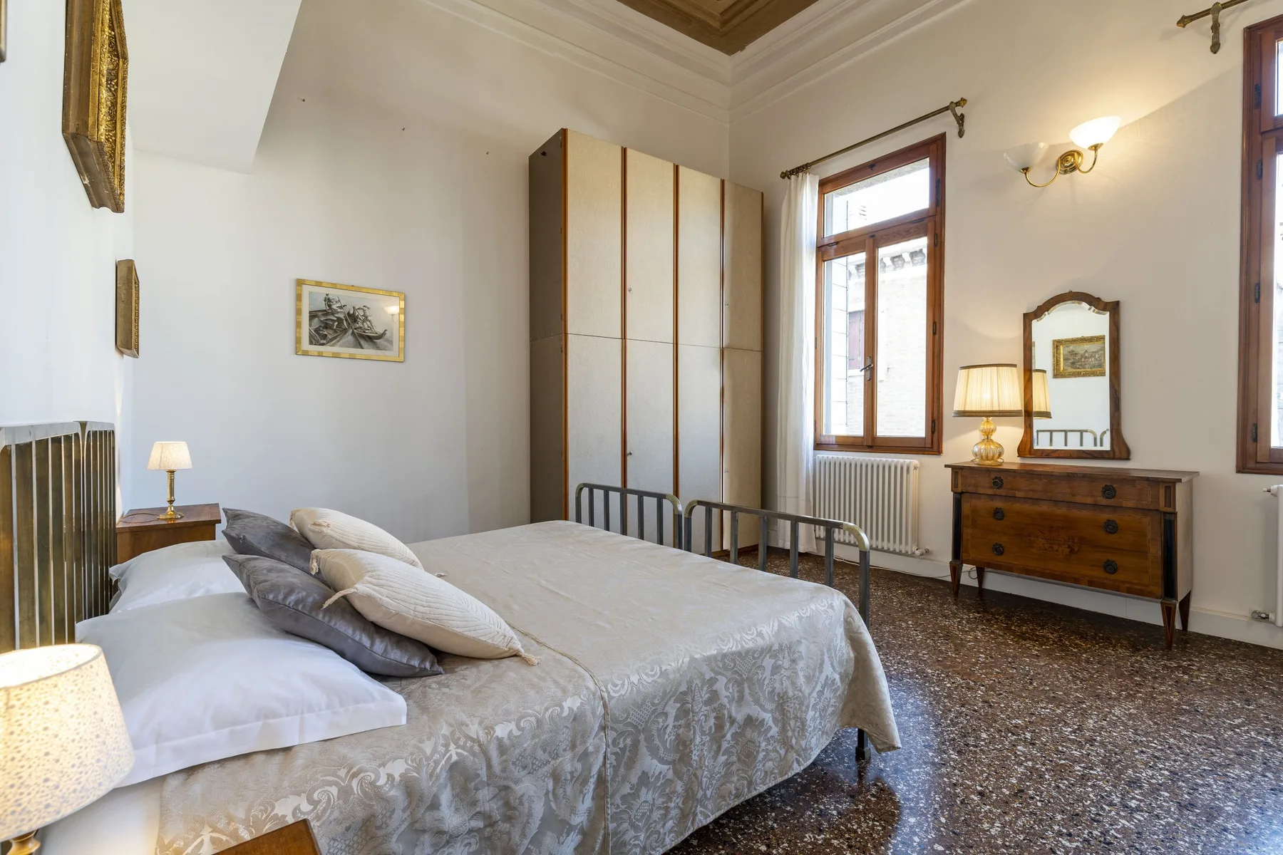 A bedroom with a large bed, a wardrobe, and a dresser beneath the window.