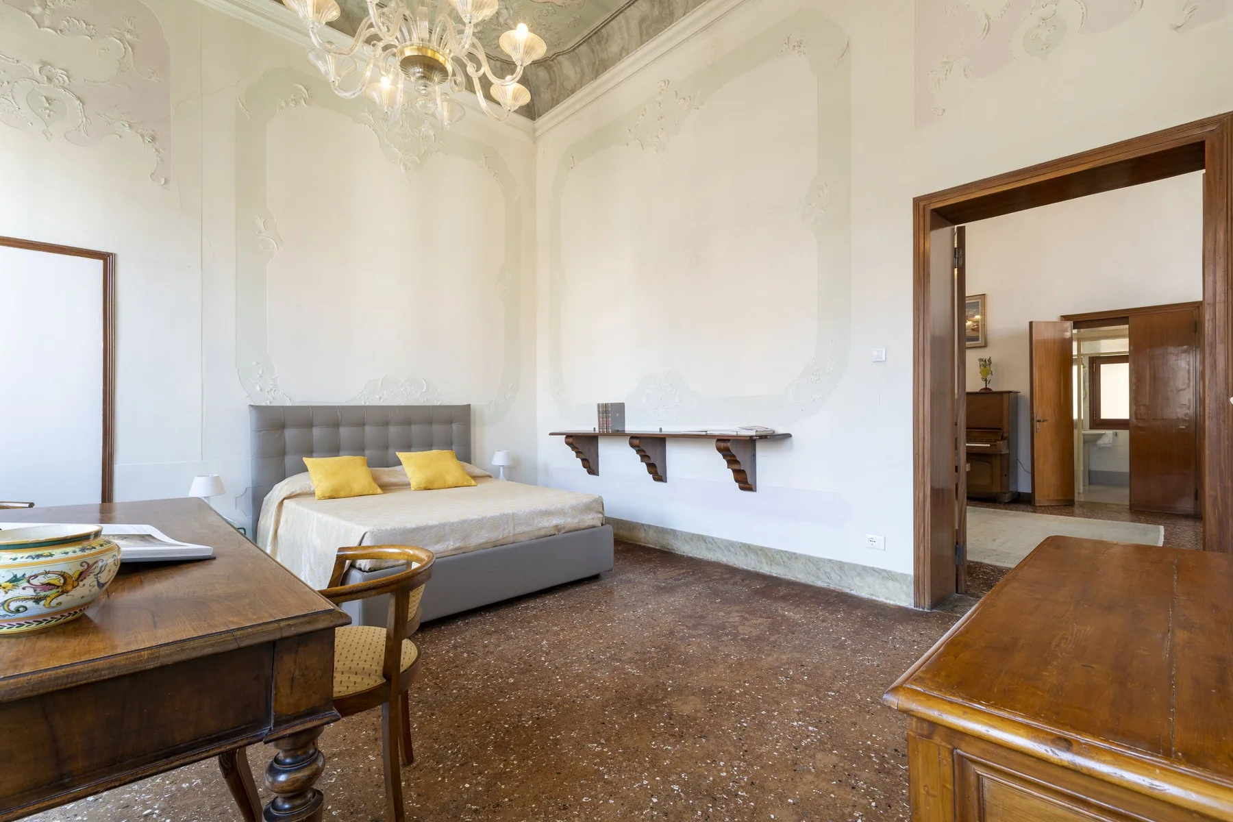 A bedroom with a bed, bedside tables, and a chandelier.