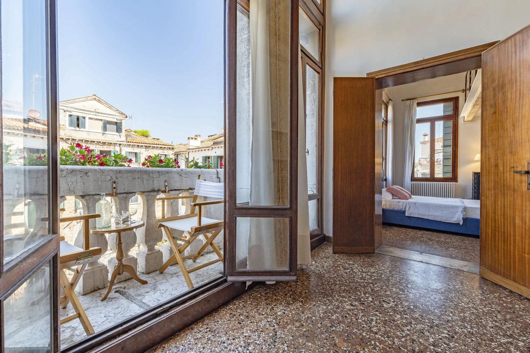 A bedroom opens onto a balcony with outdoor seating and city views.