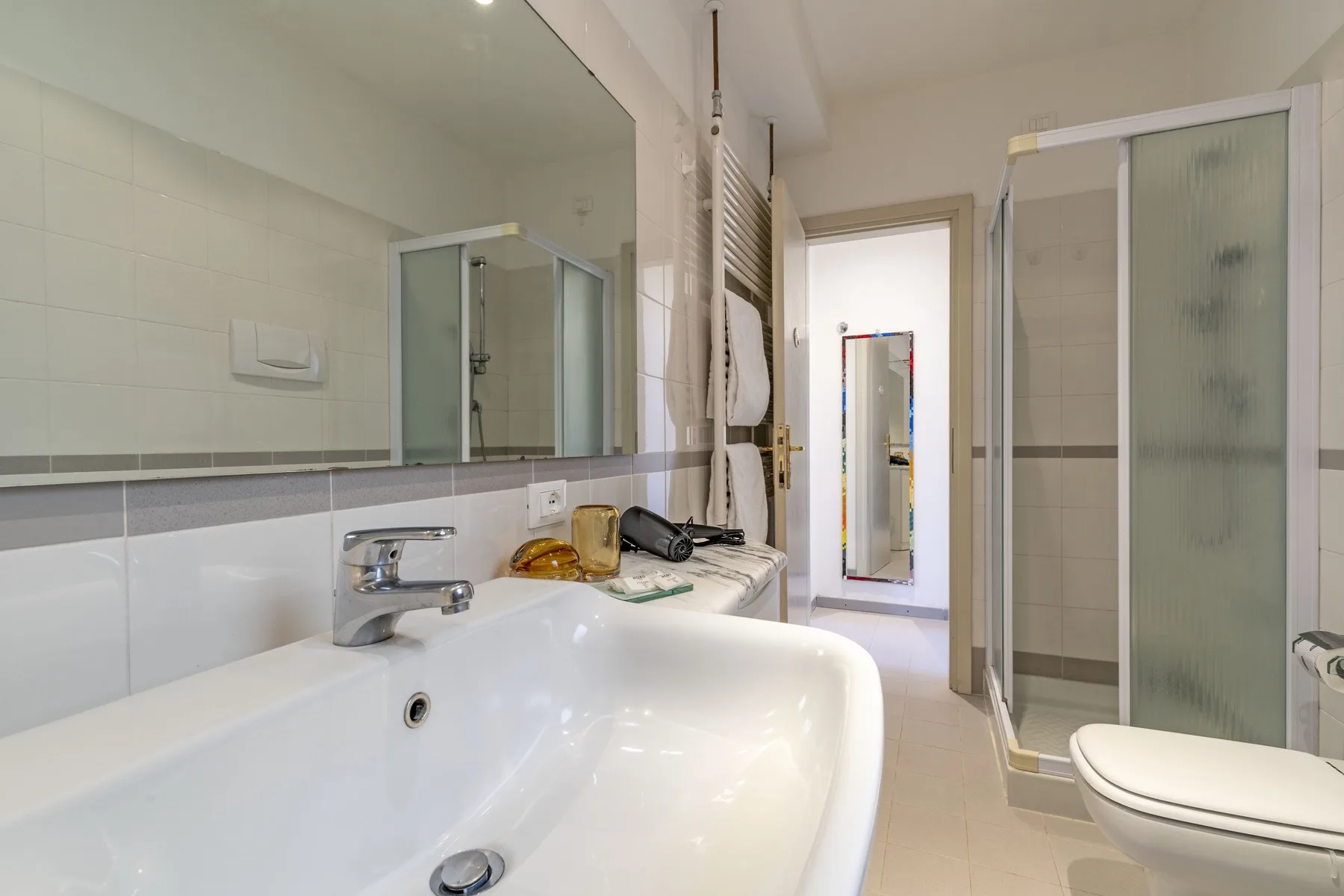 A tiled bathroom with a bathtub, sink, and glass shower enclosure.