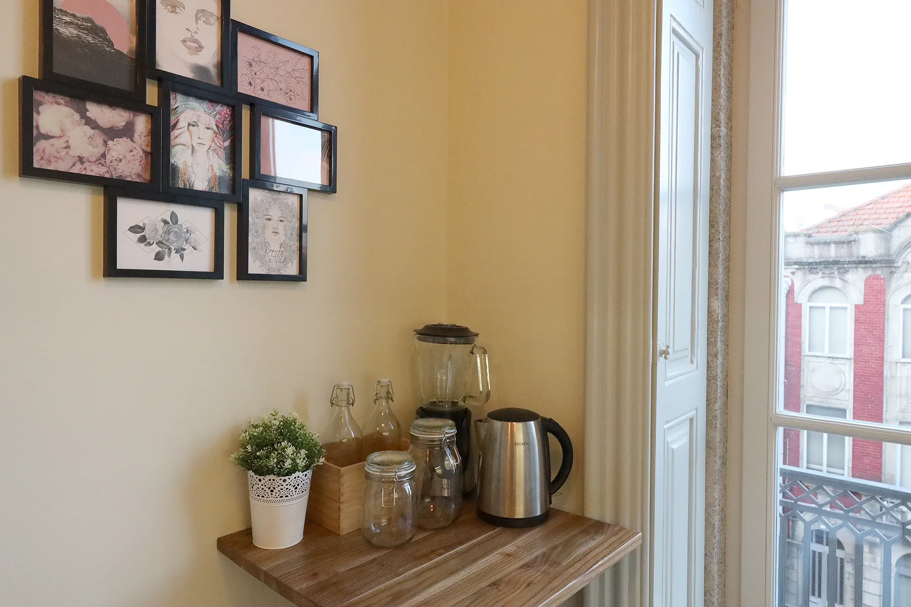 A small refreshment station sits beside a tall window with framed artwork on the wall.