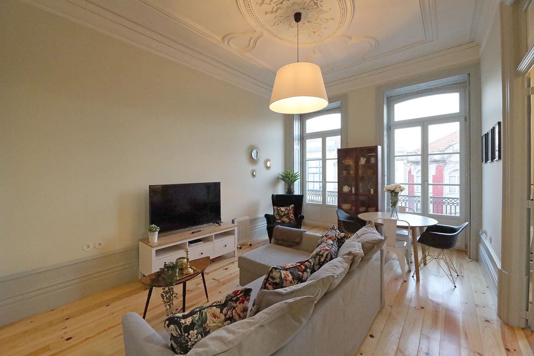 A bright living room with seating, a television, and tall windows.