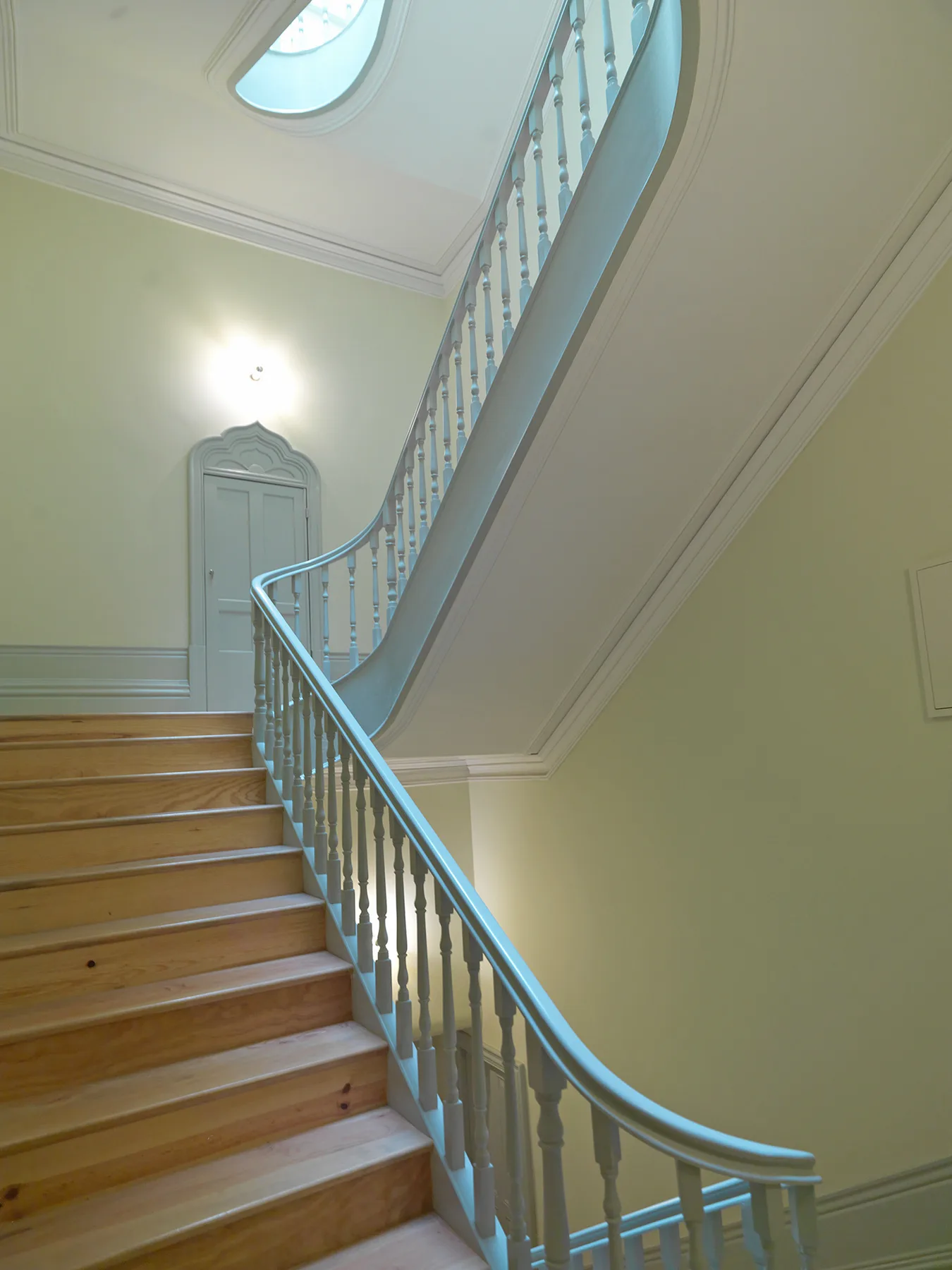 A curved staircase with wooden steps and a pale painted railing.