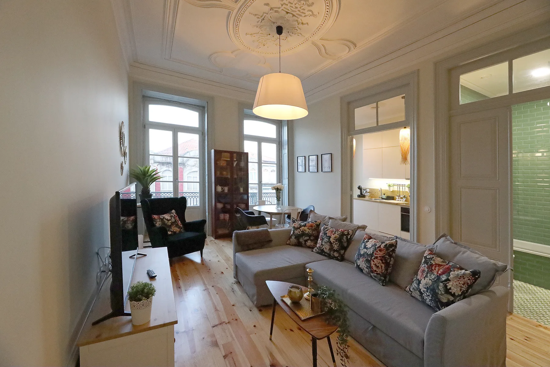 A living room with a gray sectional sofa, coffee table, and tall windows.