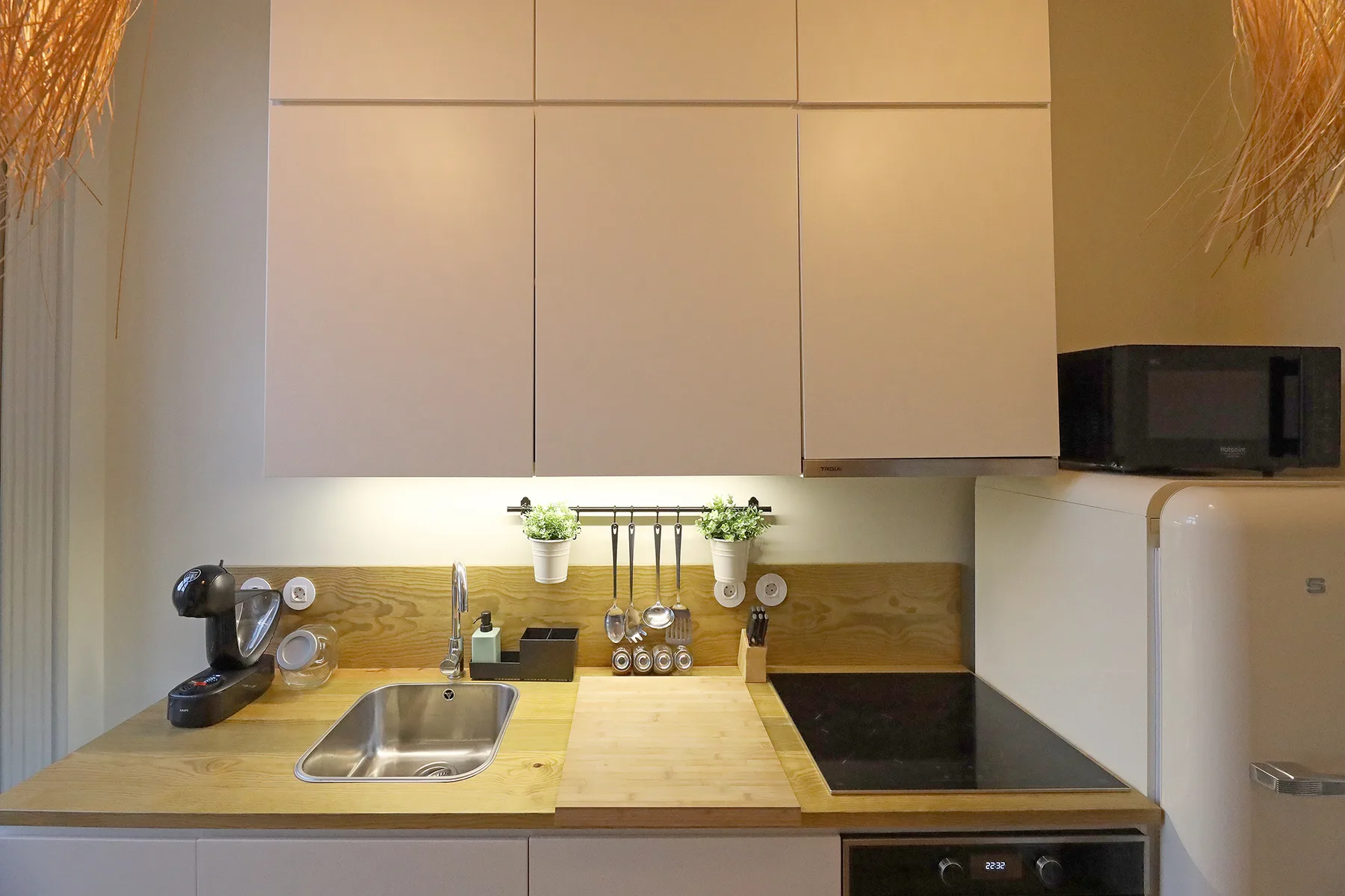 A compact kitchen with a sink, cooktop, and overhead cabinets.