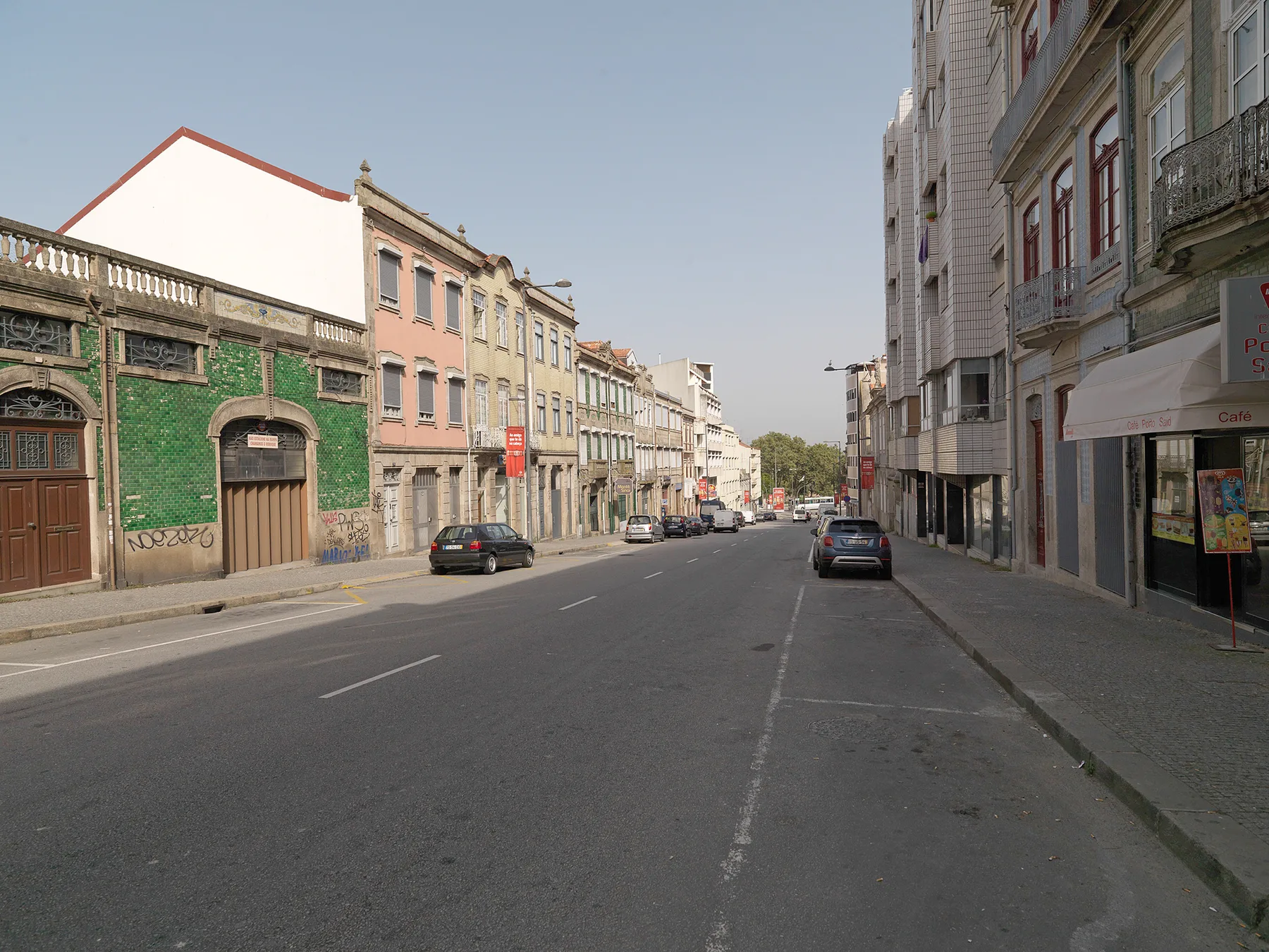 A city street lined with multistory buildings and parked cars.