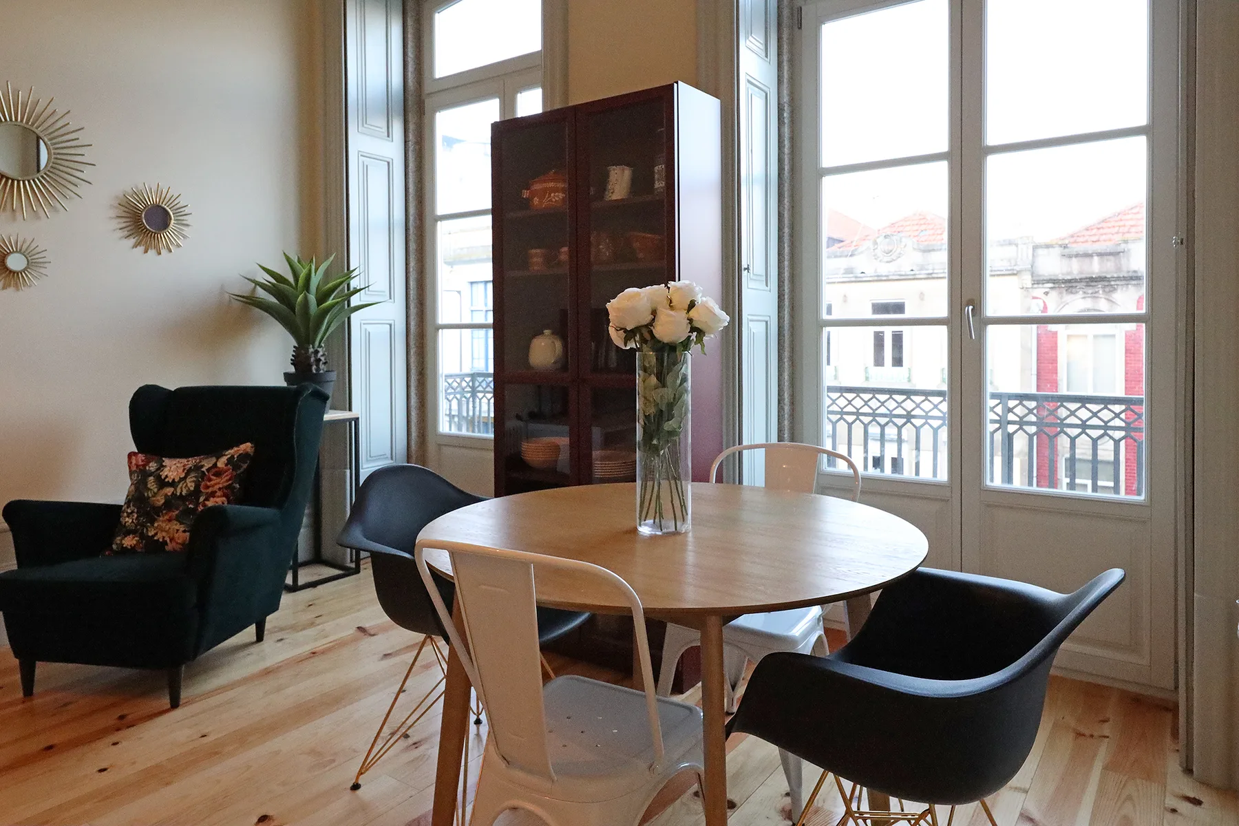 A bright dining and sitting area with a round table beside tall windows.