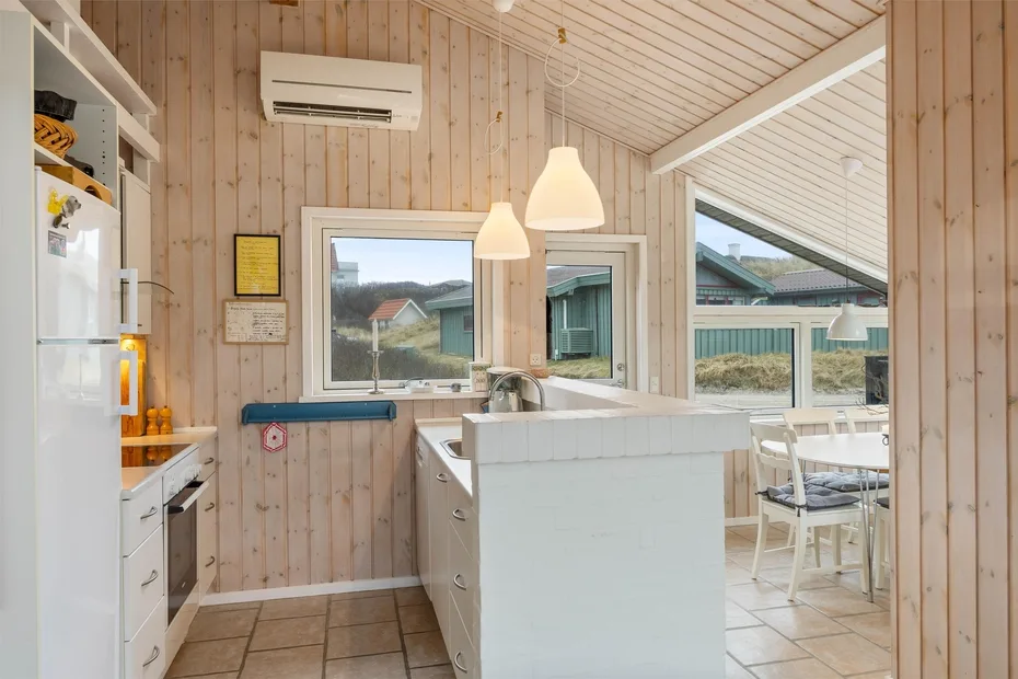 Una cocina luminosa con una encimera central y ventanas con vistas a edificios cercanos.