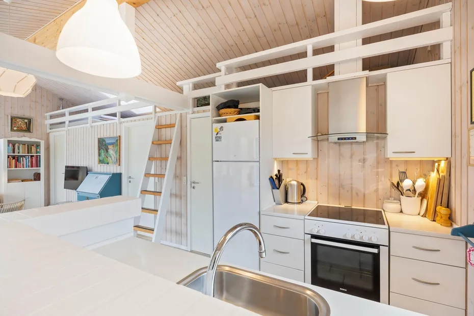 Una cocina luminosa con armarios blancos, una placa de cocina y un fregadero.