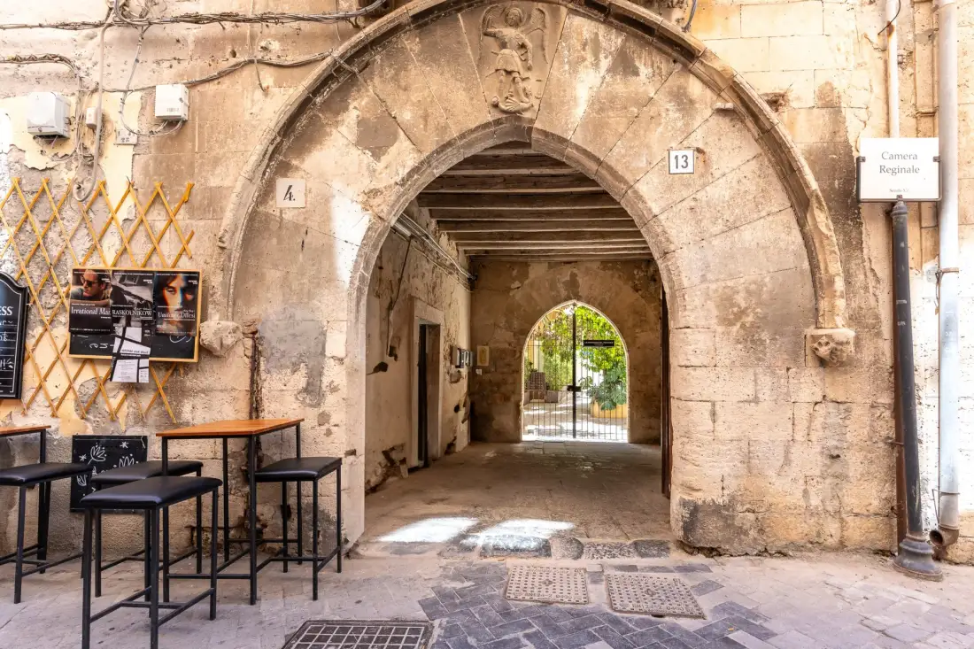 Un pasaje de piedra con arco se abre a un patio cerrado.