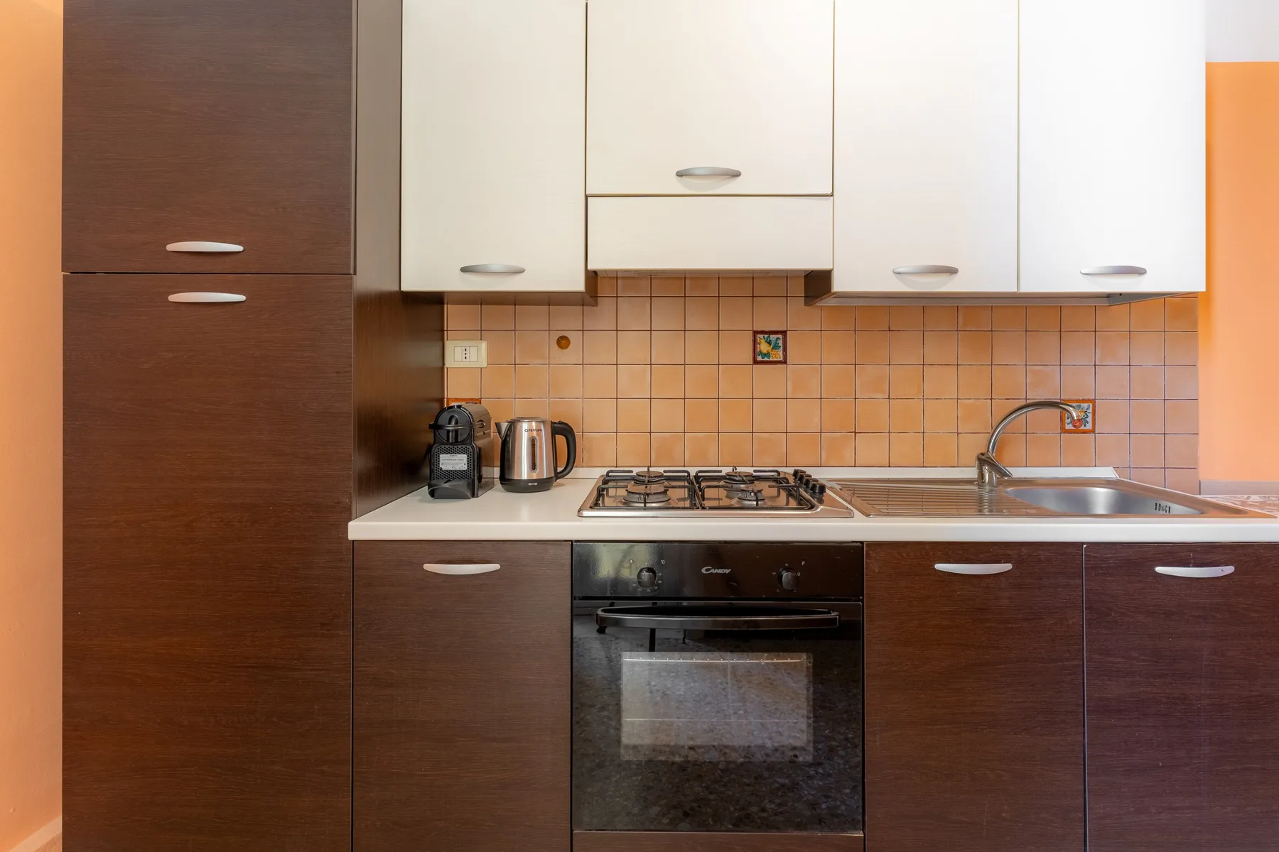 Una cocina con gabinetes oscuros, un salpicadero de azulejos y un horno integrado.