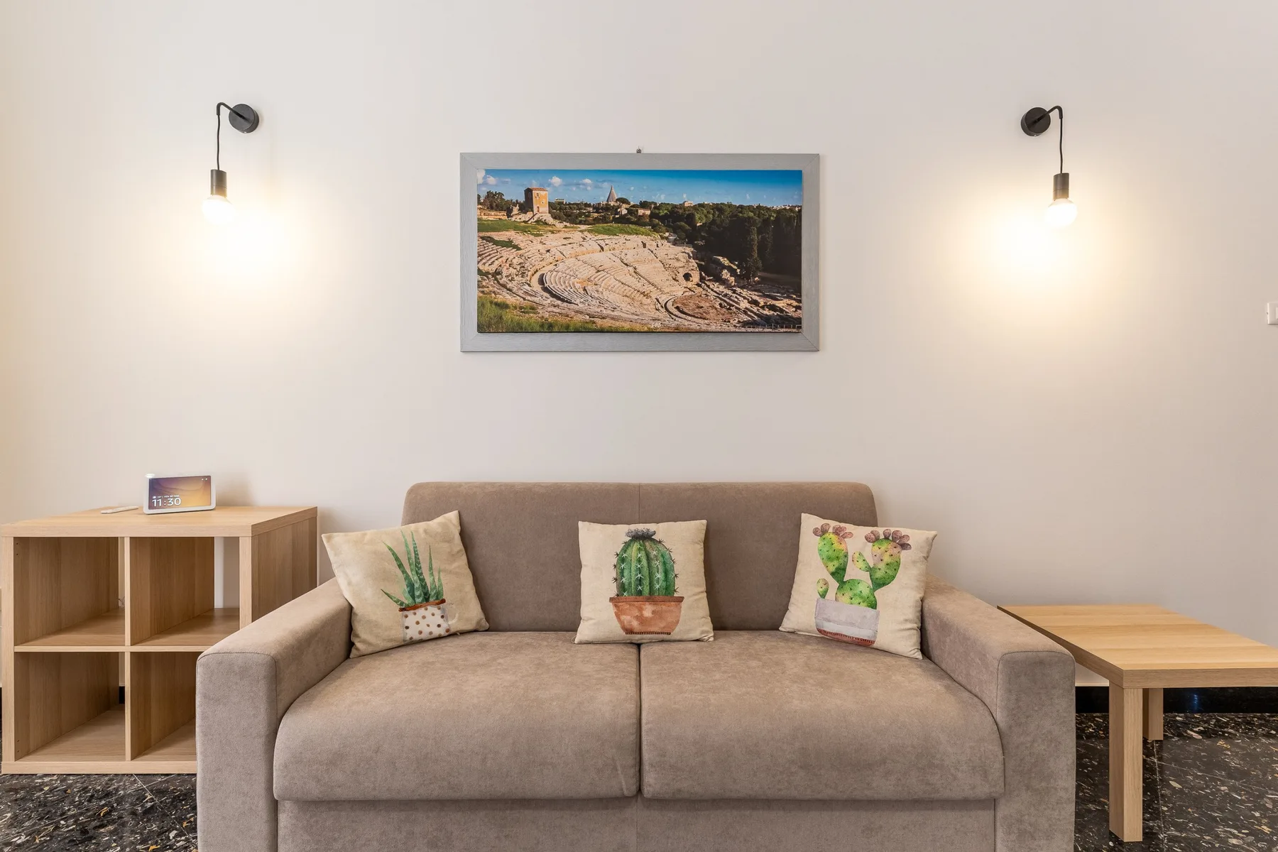 Una sala de estar con un sofá debajo de un cuadro de paisaje.