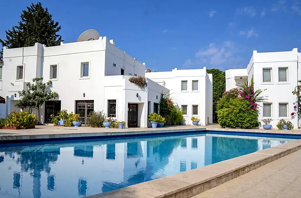 Piscina y edificios blancos de habitaciones que la rodean