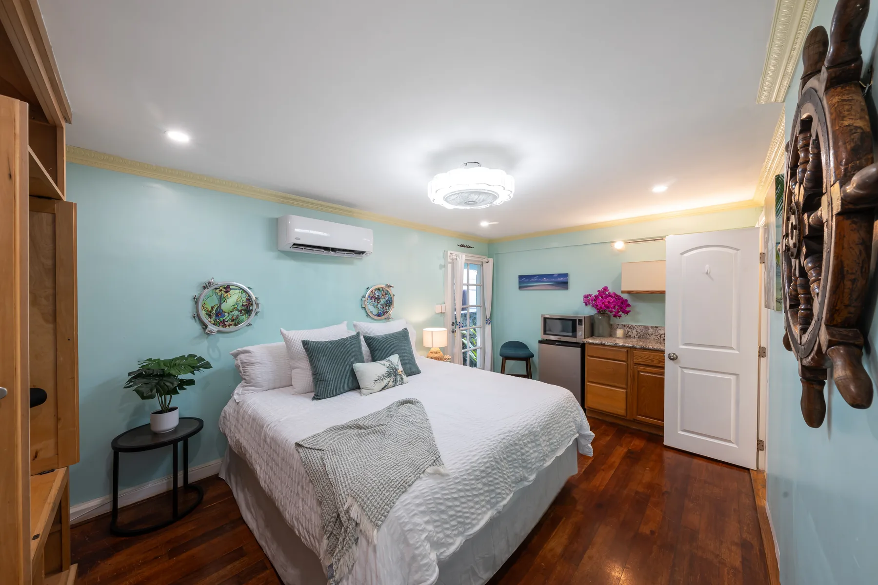 Un dormitorio con una cama blanca y una pequeña cocina junto a la pared.