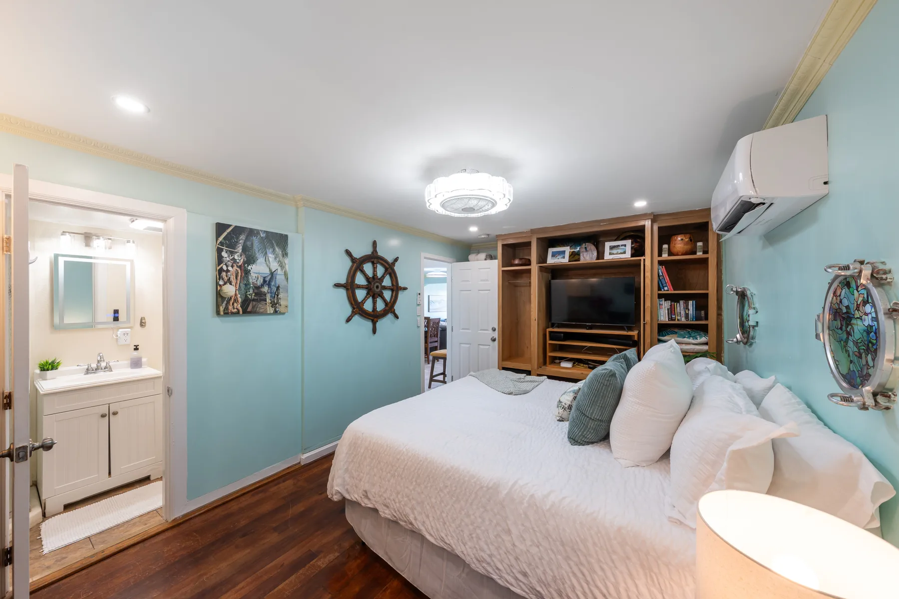 Un dormitorio con una cama grande, estanterías de madera y paredes azul claro.