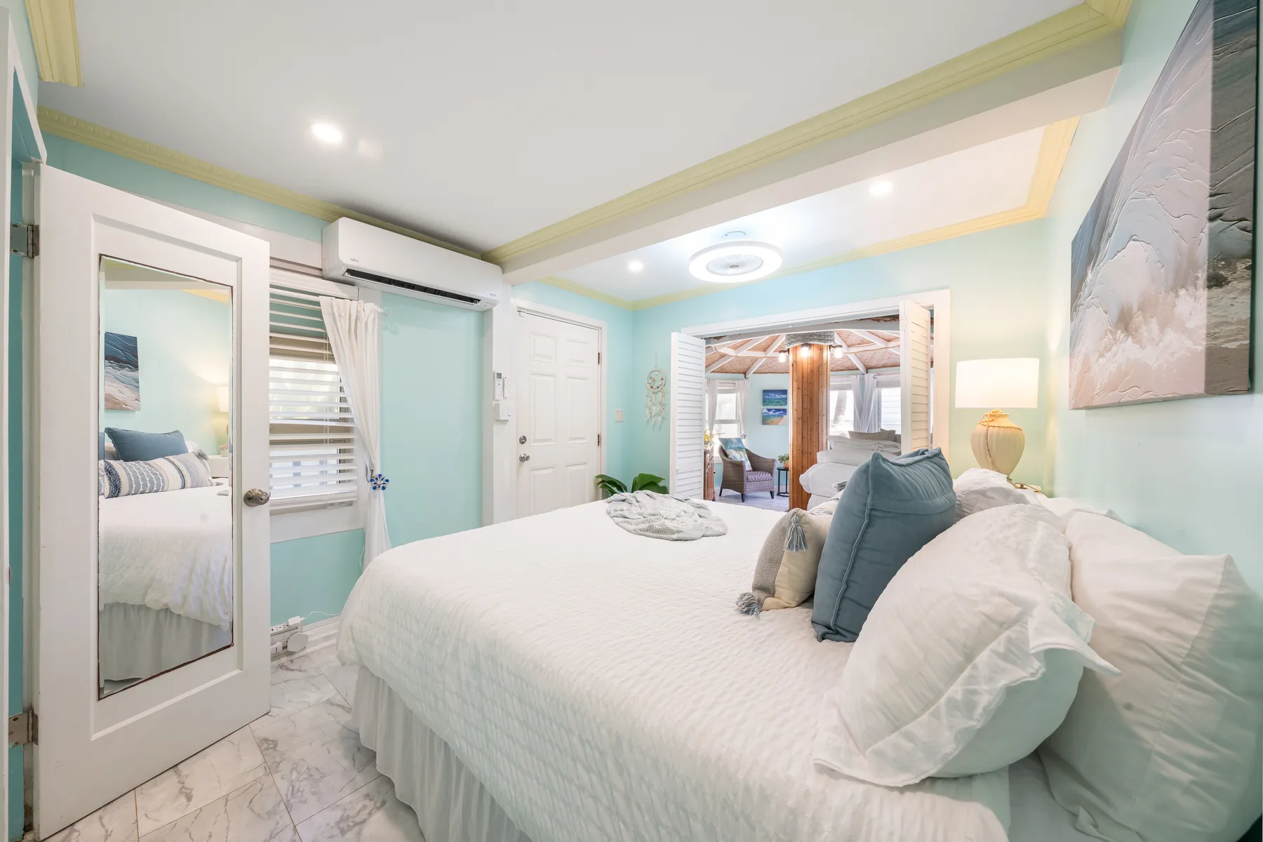 Un dormitorio luminoso con una cama arreglada y una puerta abierta a una habitación contigua.